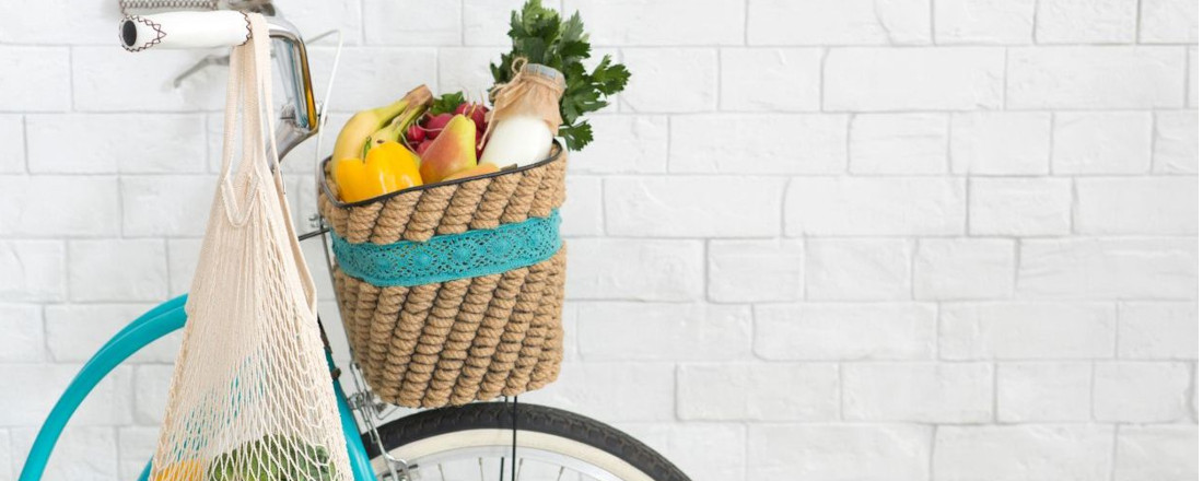 A bike against a white stone wall with food in its front basket